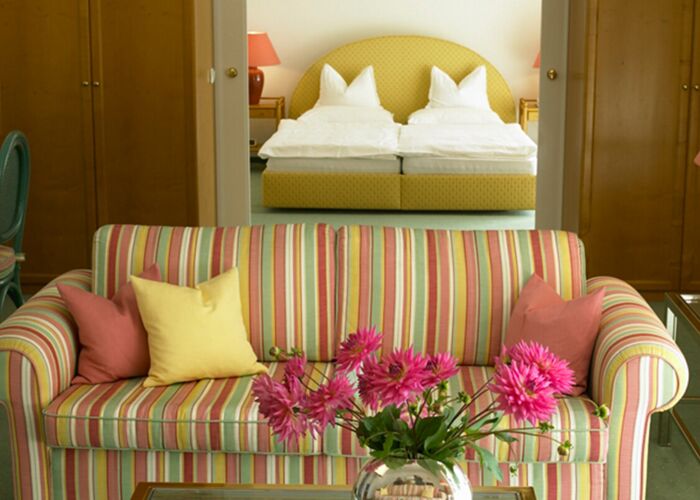 Eine bunte Couch steht vor dem Schlafzimmer der Suite vom Hotel Seehof Mondsee