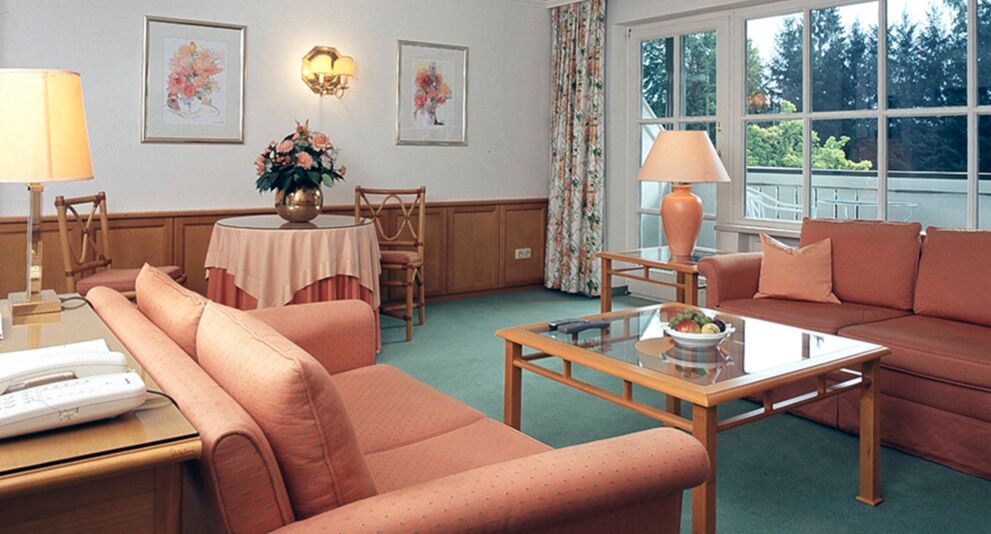 A hotel room with seating set and table including a balcony in the Salzkammergut region