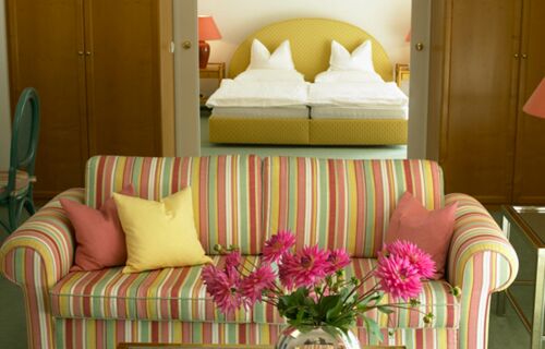 Eine bunte Couch steht vor dem Schlafzimmer der Suite vom Hotel Seehof Mondsee