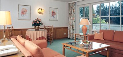 A hotel room with seating set and table including a balcony in the Salzkammergut region