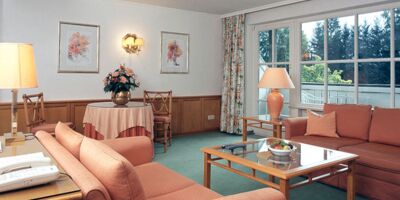 Ein Hotelzimmer mit Sitzgarnitur und Tisch samt einem Balkon im Salzkammergut