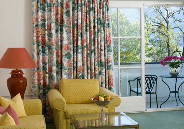 A hotel room with a seating set and table, with a balcony overlooking the lake