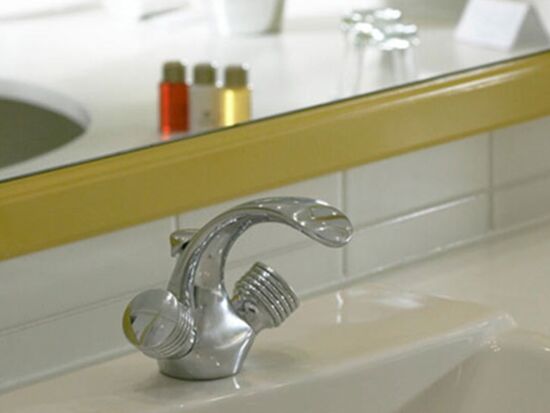 A washbasin with a tap and a mirror in the bathroom of the Hotel Seehof Mondsee