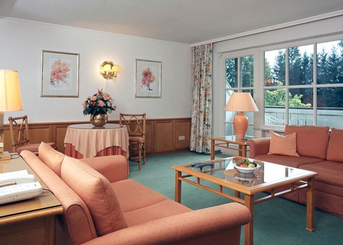 Ein Hotelzimmer mit Sitzgarnitur und Tisch samt einem Balkon im Salzkammergut