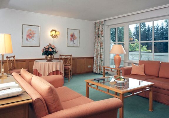 A hotel room with seating set and table including a balcony in the Salzkammergut region