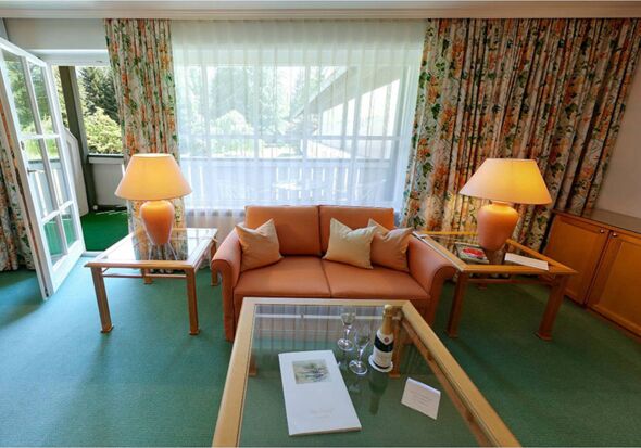 Eine Suite mit Sitzgarnitur und Tisch samt einem Balkon im Salzkammergut