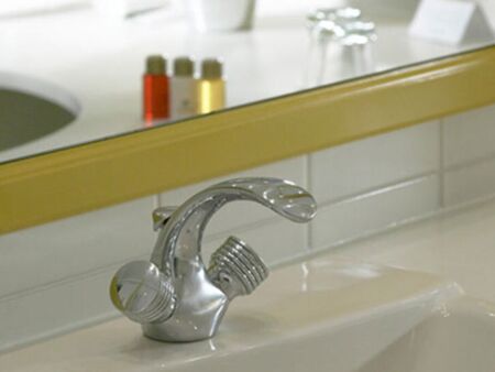 A washbasin with a tap and a mirror in the bathroom of the Hotel Seehof Mondsee