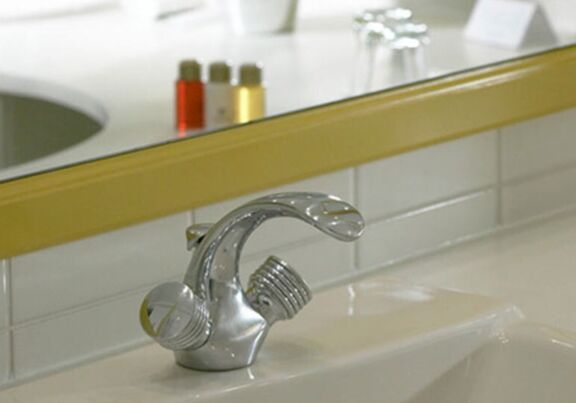 A washbasin with a tap and a mirror in the bathroom of the Hotel Seehof Mondsee