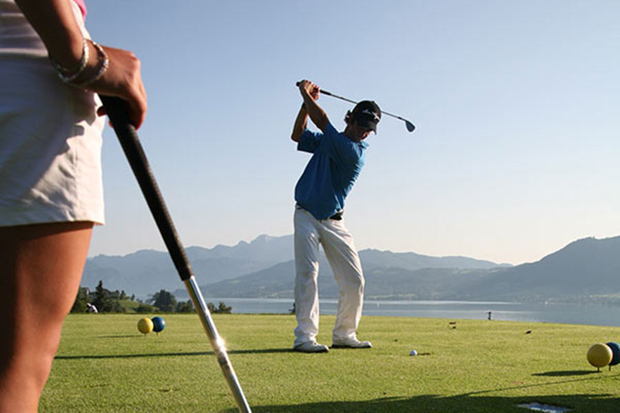 Couple playing golf on Mondsee, in the background a fantastic mountain panorama is visible