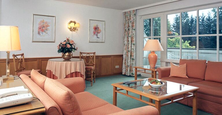 A hotel room with seating set and table including a balcony in the Salzkammergut region