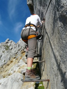 Kletterin gesichert auf einem Klettersteig im Felsen