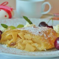 Stück Apfelstrudel dekoriert mit Kirschen und Zucker