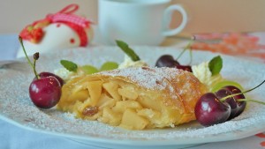 Stück Apfelstrudel dekoriert mit Kirschen und Zucker