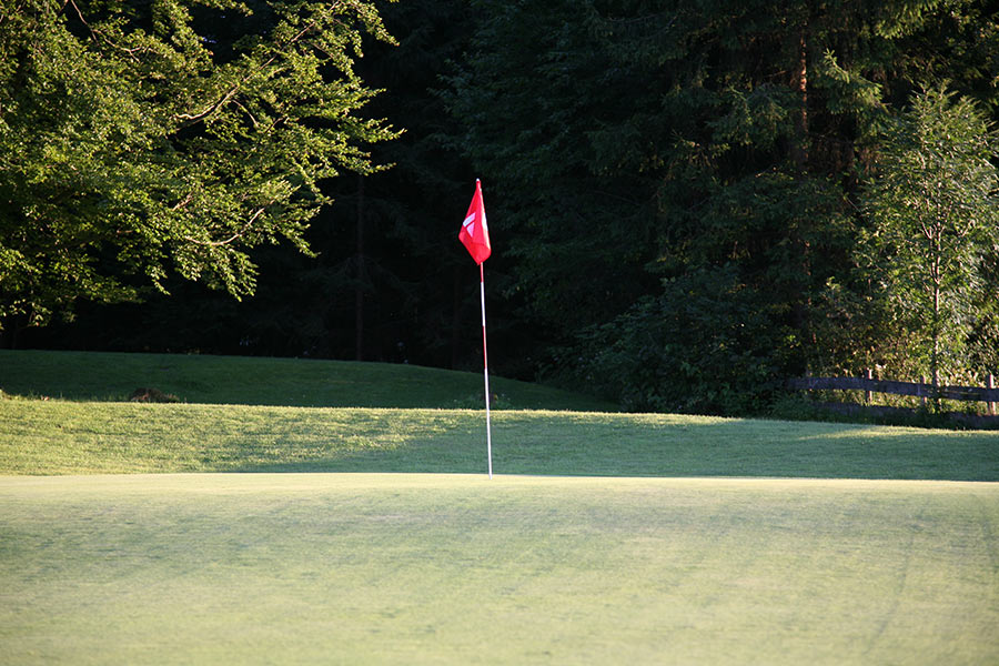 Eine Golf- Fahne markiert das Loch auf dem Golfgrün.